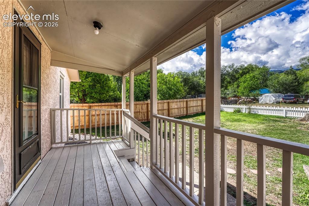 Image 3 of 41: Covered porch with wood-finish decking, solid wood railings, and a stucco e