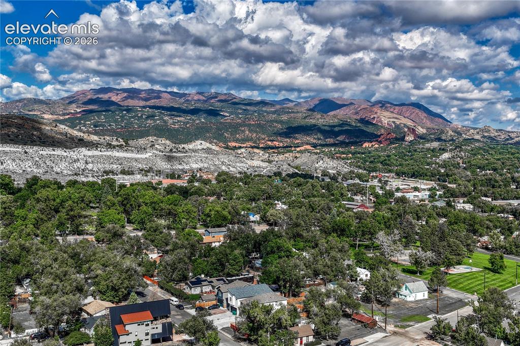 Image 37 of 41: Expansive tree-lined neighborhood with distant mountain ranges and scattere