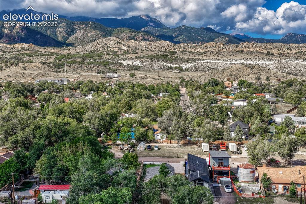 Image 38 of 41: Expansive mountain backdrop with a residential area featuring mature trees 
