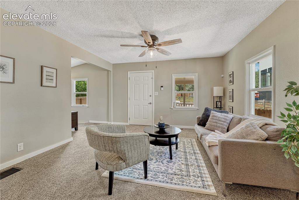 Image 4 of 41: Bright and spacious living area featuring neutral wall finishes, ceiling fa
