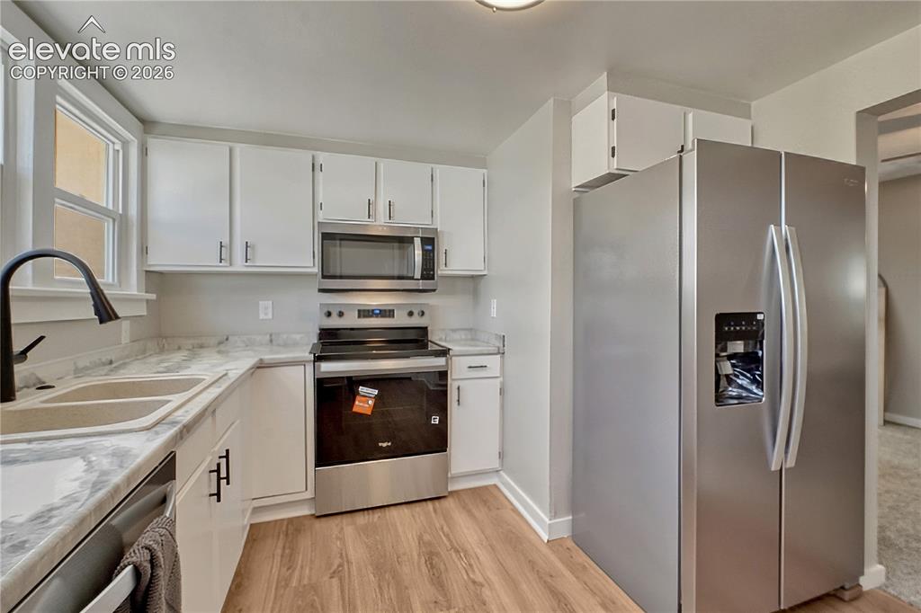 Image 9 of 41: Kitchen featuring stainless steel appliances, wood-finish flooring, white c