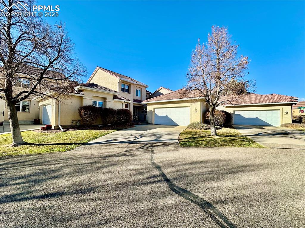 Caption: View of front of home with stucco siding, driveway, a garage, and a tiled roof