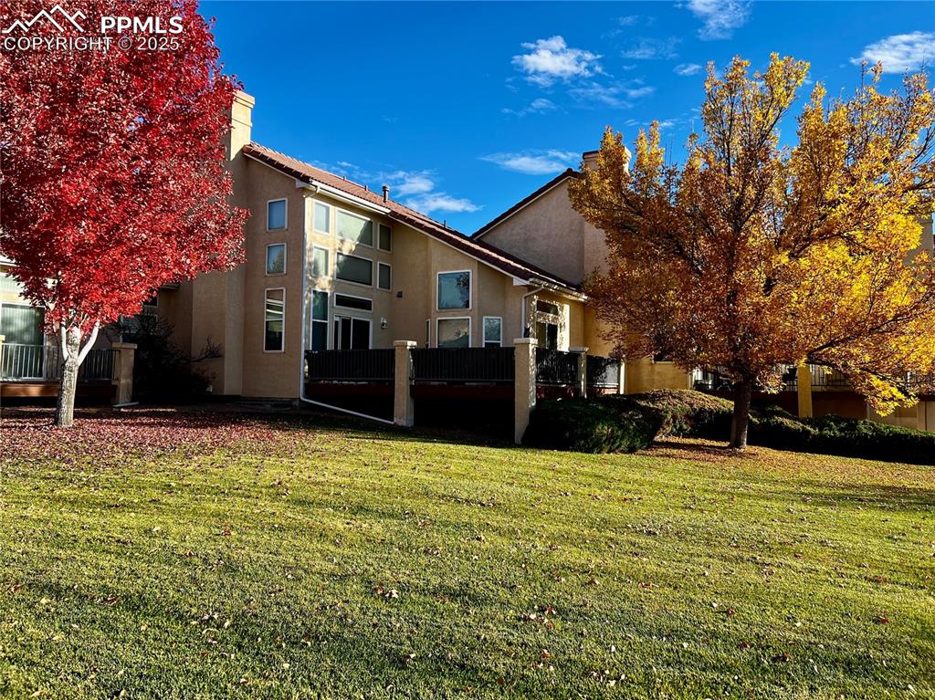 Image 36 of 41: Rear view of house with stucco siding, a lawn, and a chimney