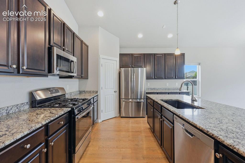 Image 10 of 40: Kitchen featuring dark wood cabinetry, light-colored granite countertops, a