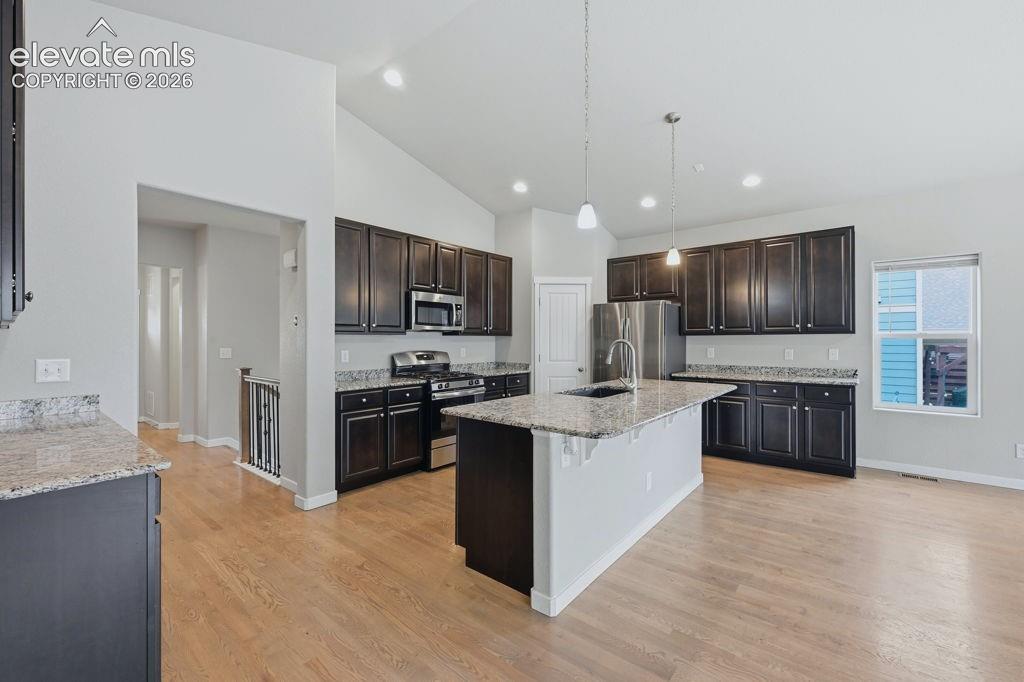 Image 13 of 40: Spacious kitchen featuring dark wood cabinetry, light-toned granite counter