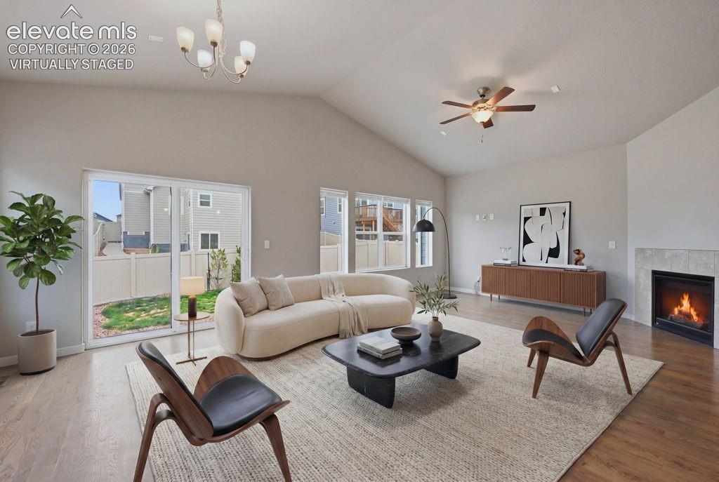 Image 14 of 40: Spacious living area featuring vaulted ceilings, wood-finish flooring, and