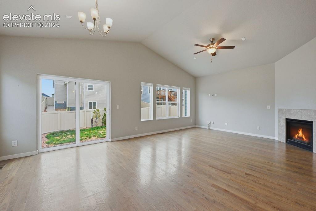 Image 15 of 40: Spacious living area featuring vaulted ceilings, wood-finish flooring, a ti