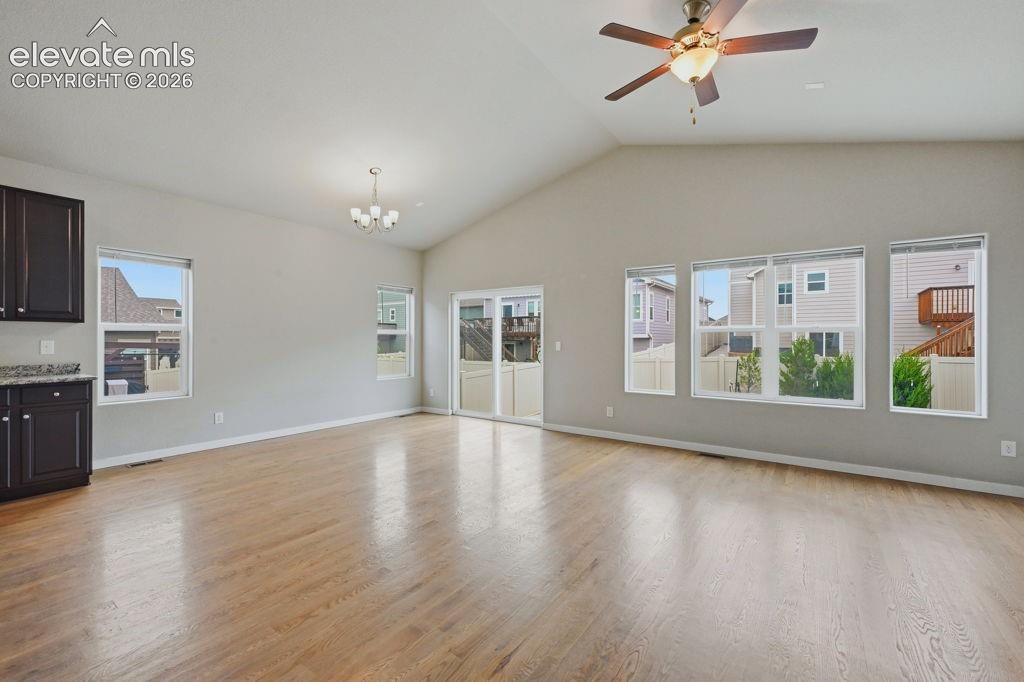 Image 16 of 40: Spacious living area featuring vaulted ceilings, wood-finish flooring, ampl