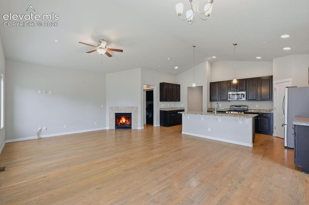 Image 17 of 40: Spacious living area featuring wood-finish flooring, a fireplace with a lig