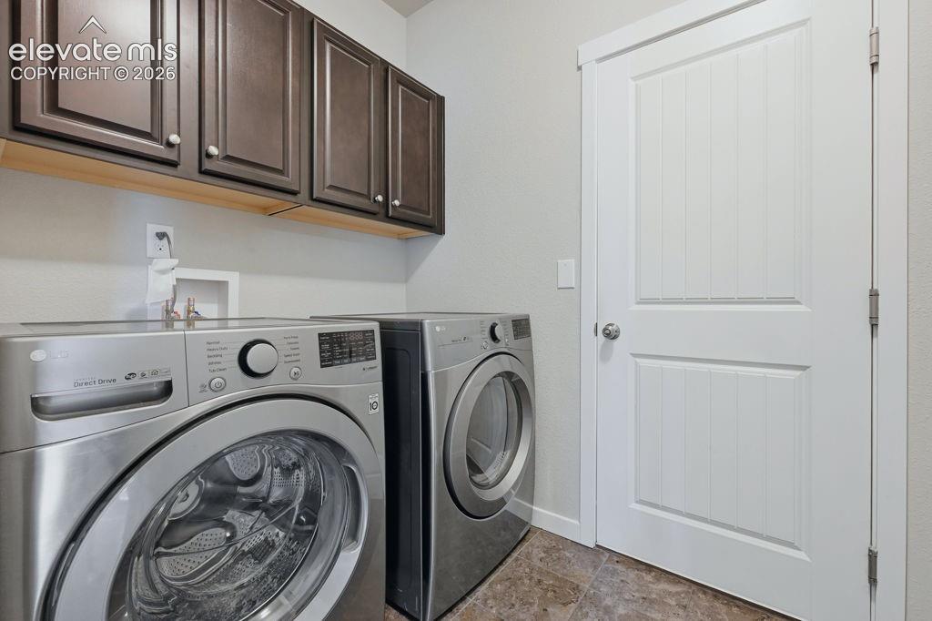 Image 20 of 40: Dedicated laundry area featuring dark wood cabinetry for storage, light wal