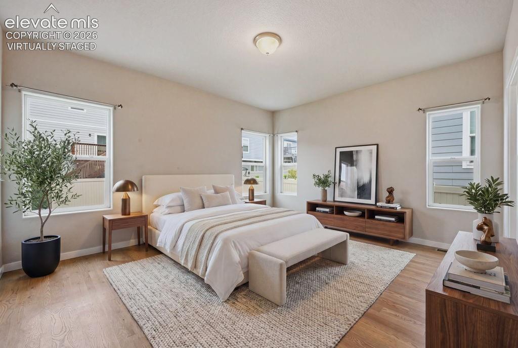 Image 21 of 40: Spacious bedroom featuring light wood-finish flooring, light-colored walls,