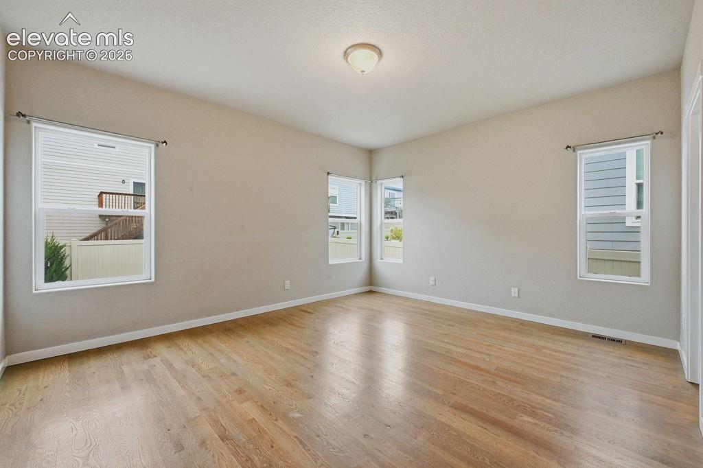 Image 22 of 40: Spacious room featuring wood-finish flooring, light neutral wall paint, whi
