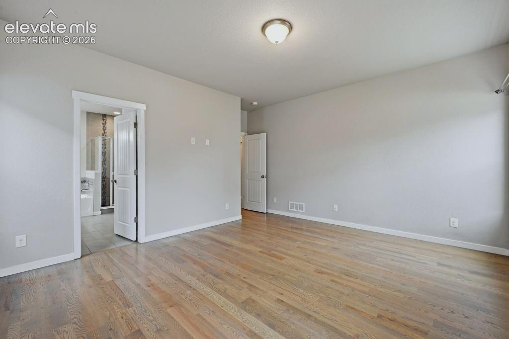 Image 23 of 40: Spacious interior featuring wood-finish flooring, light grey painted walls,
