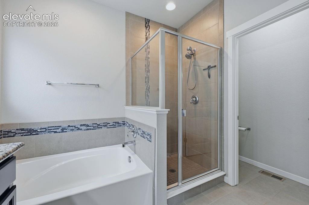 Image 25 of 40: Bathroom featuring a built-in tub, enclosed shower with a glass door, and t