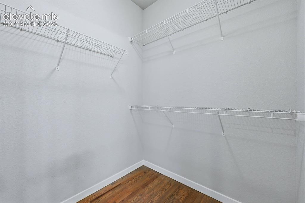 Image 26 of 40: Ample closet space featuring multiple white wire shelving units and wood-fi