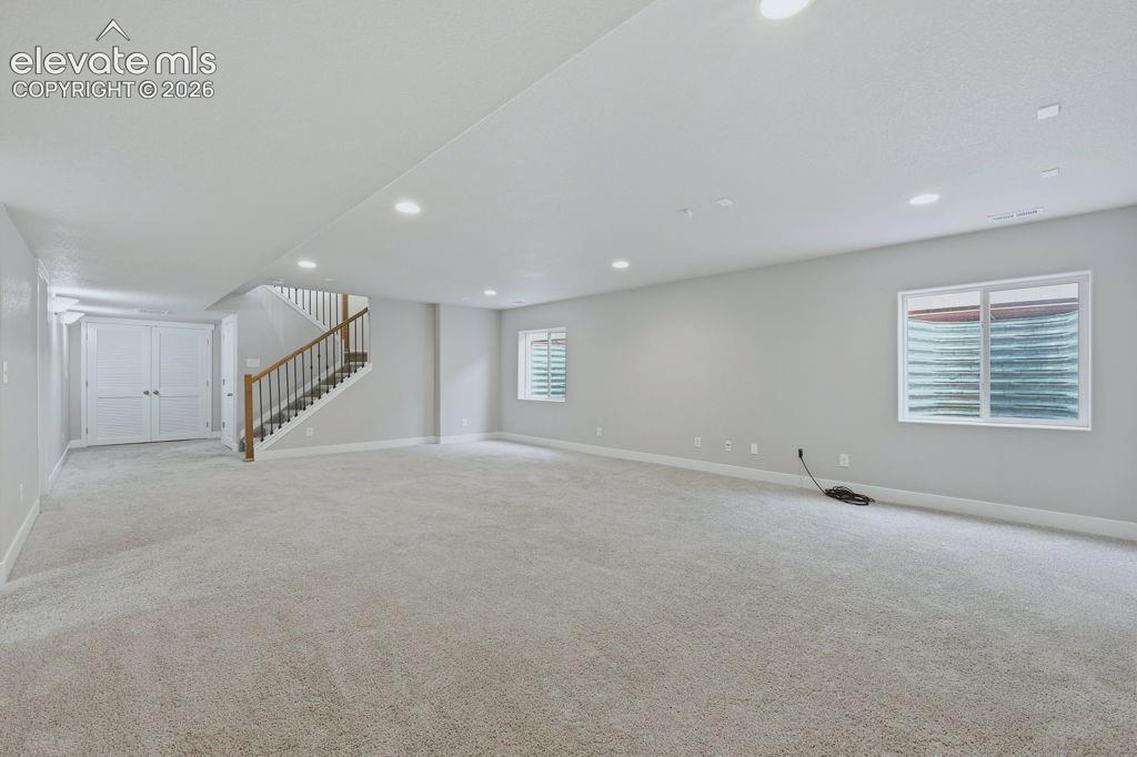 Image 28 of 40: Spacious room featuring light gray carpeting, recessed lighting, and neutra
