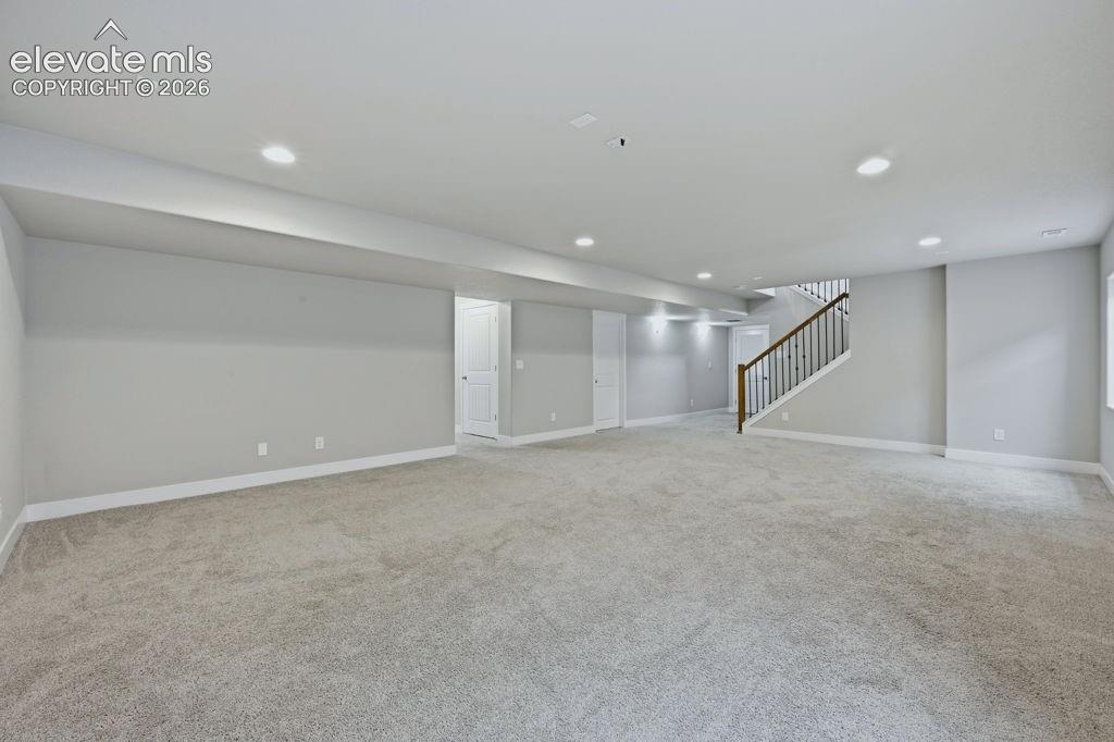 Image 31 of 40: Spacious open-concept room featuring light-toned carpet flooring, neutral p
