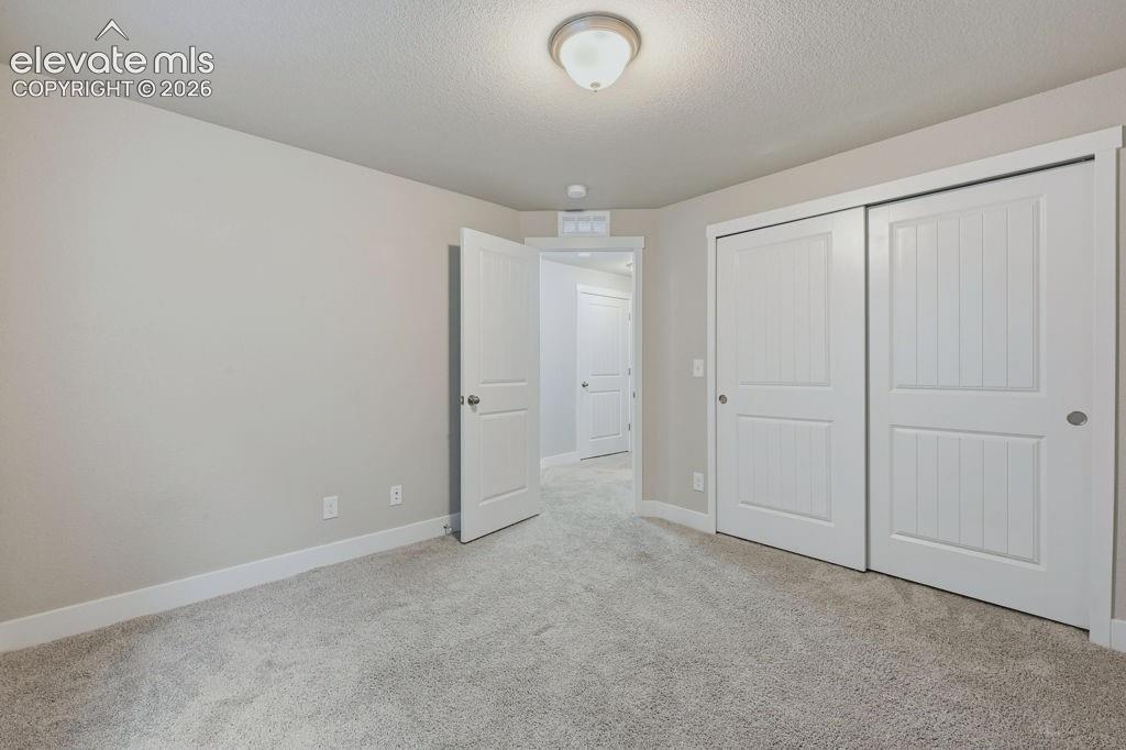 Image 33 of 40: Carpeted room featuring light gray walls, white baseboards, and a semi-flus