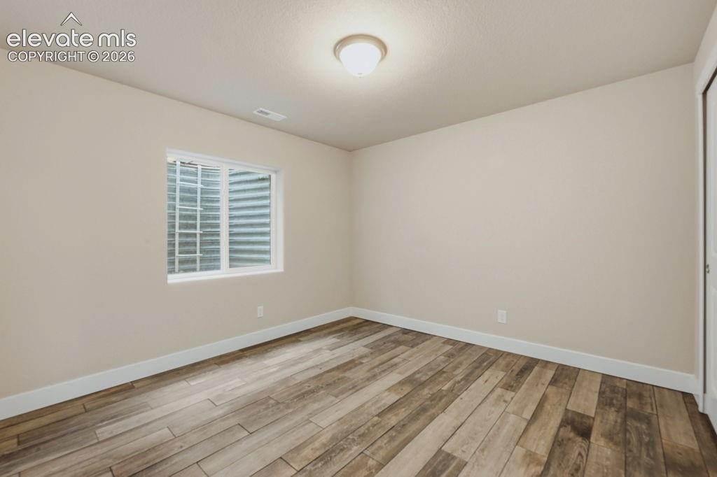 Image 35 of 40: Neutral toned room featuring wood-finish flooring, white baseboards, and a
