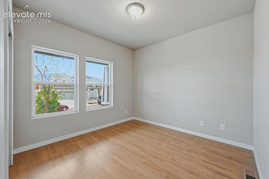 Image 6 of 40: Hardwood-style flooring throughout this room with two windows, a ceiling-mo