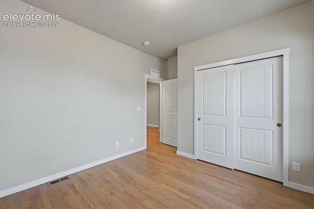 Image 7 of 40: Bedroom featuring wood-finish flooring, light grey painted walls, white bas