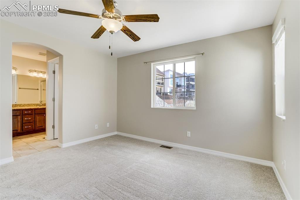 Image 21 of 35: Unfurnished bedroom featuring light carpet, arched walkways, ceiling fan, a