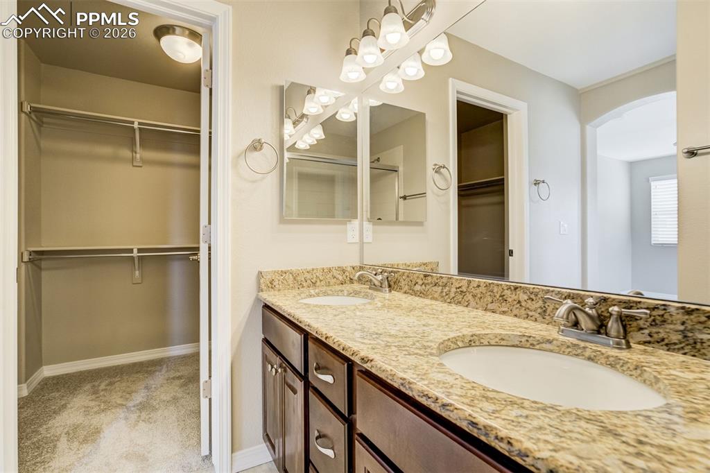 Image 23 of 35: Full bathroom with a walk-in closet, double vanity, and large walk-in close