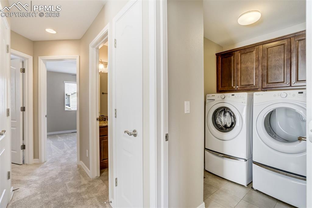 Image 27 of 35: Laundry area upstairs with cabinet space, washing machine and clothes dryer