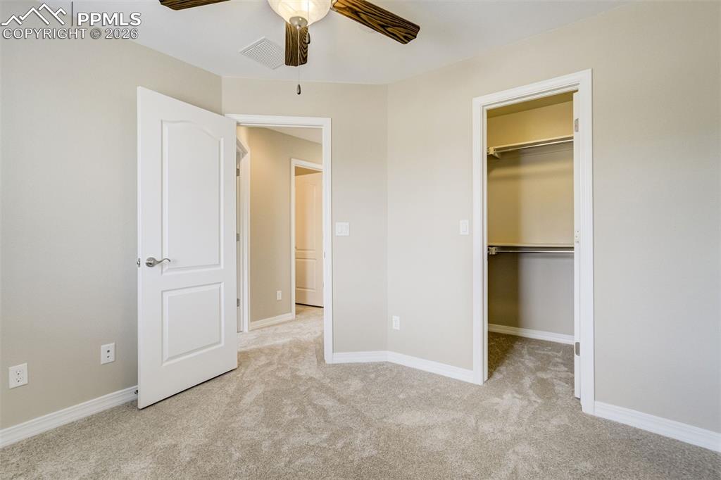 Image 29 of 35: Bedroom 2 with a spacious closet, light carpet, and ceiling fan