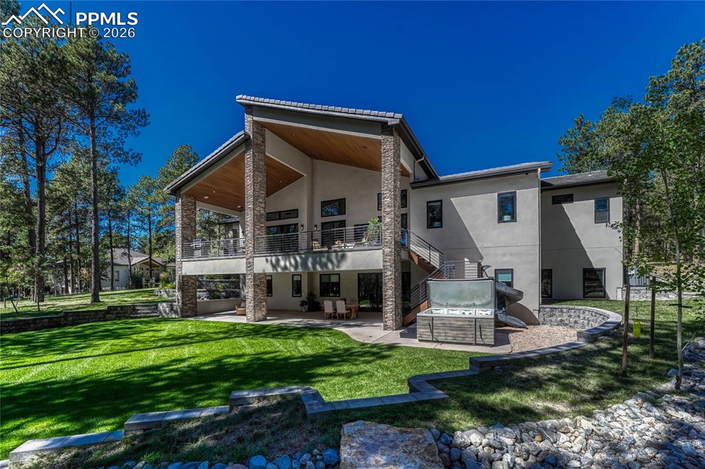 Image 12 of 49: Back of property with a patio area, stucco siding, a lawn, and a balcony