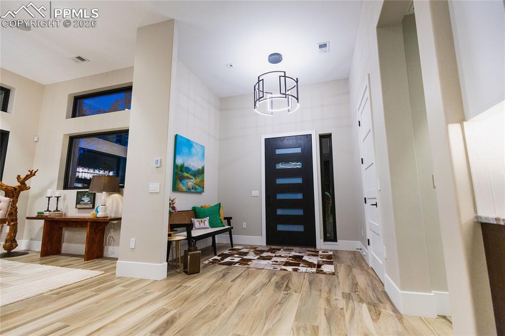 Image 14 of 49: Entrance foyer with light wood-style floors and suspended lighting