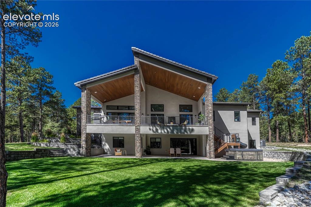Image 39 of 49: Back of property featuring stucco siding, a patio area, a lawn, and a balco
