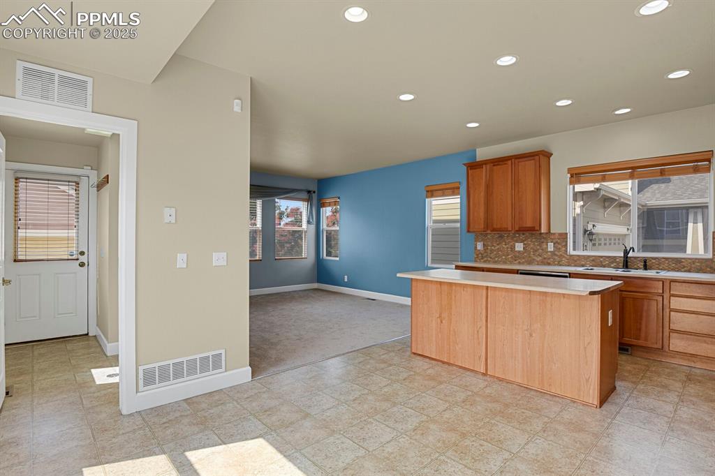 Image 14 of 35: Kitchen with a kitchen island, light countertops, tasteful backsplash, rece