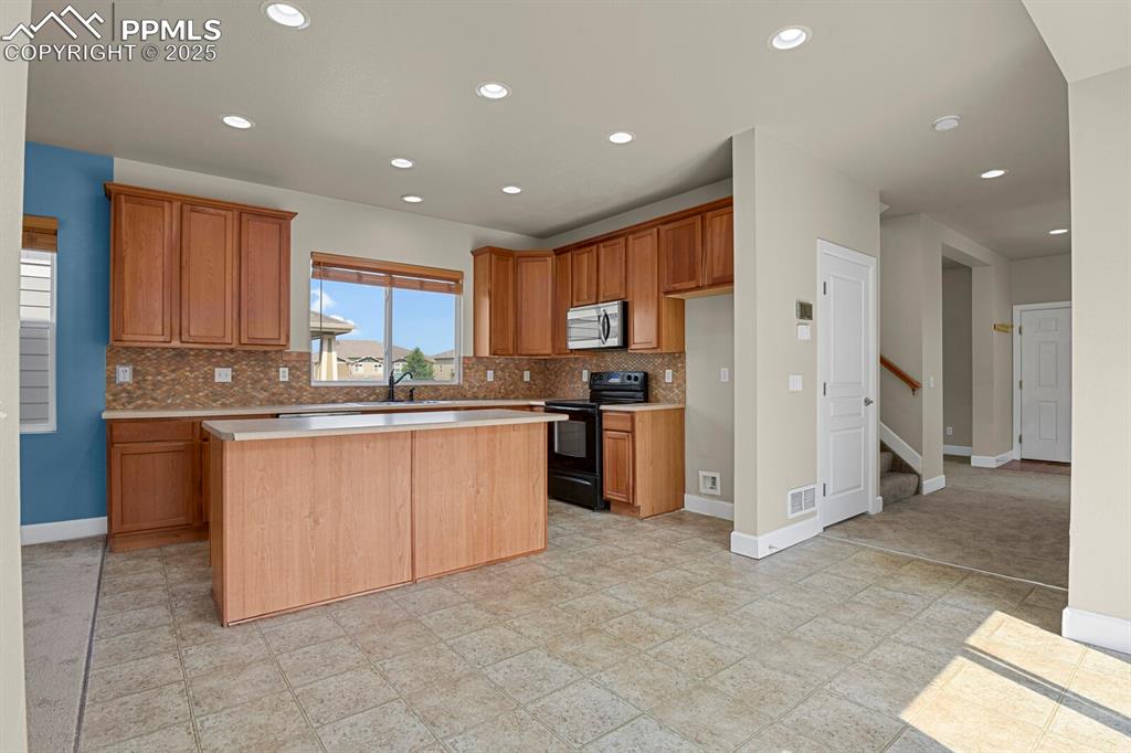 Image 15 of 35: Kitchen featuring black electric range, light countertops, decorative backs