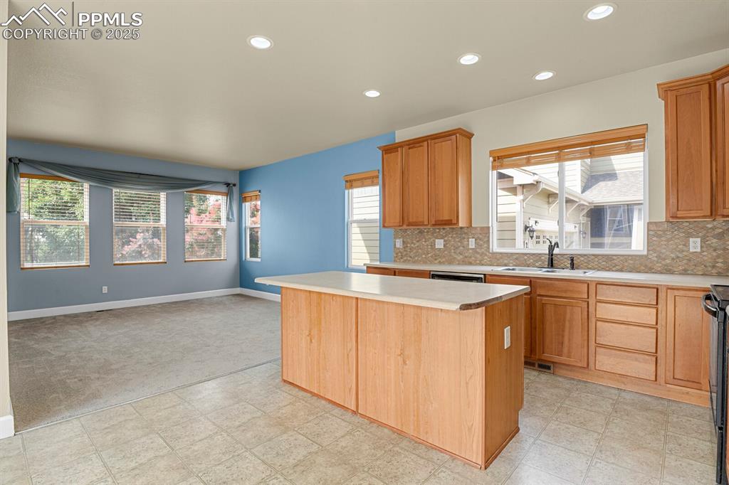 Image 17 of 35: Kitchen with a kitchen island, light countertops, backsplash, healthy amoun