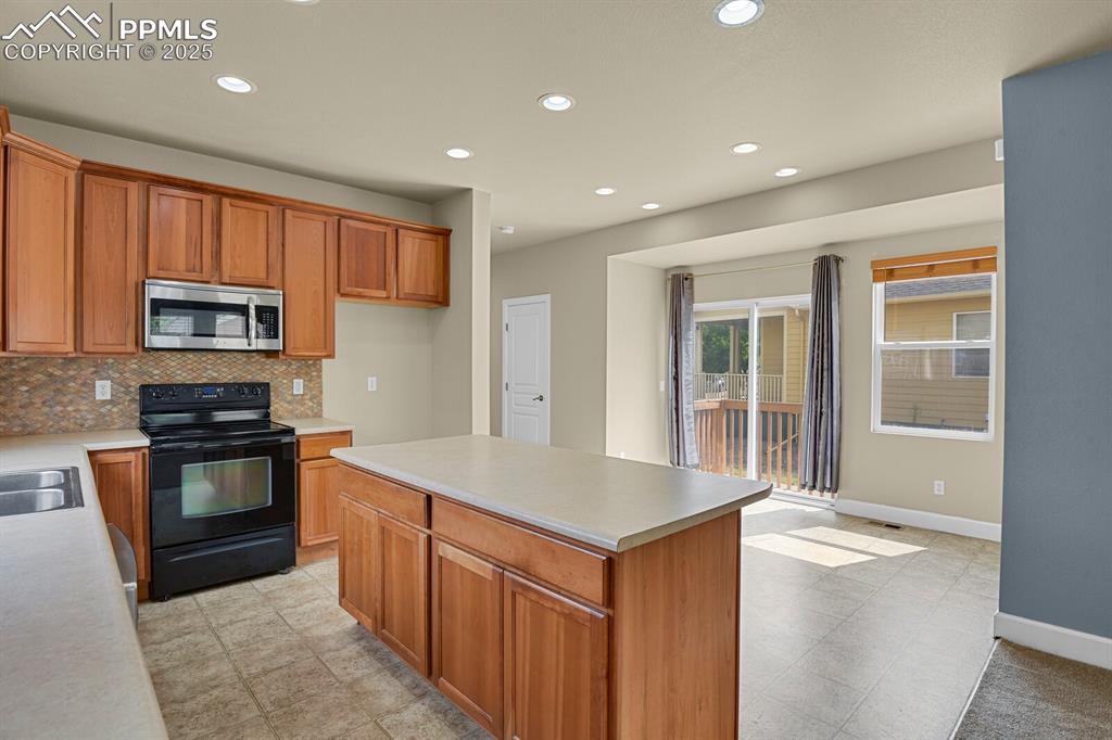 Image 18 of 35: Kitchen featuring black electric range, stainless steel microwave, light co