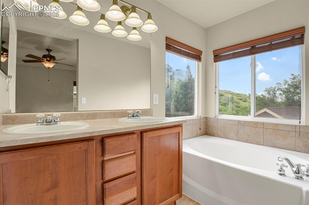 Image 32 of 35: Full bathroom featuring a bath, double vanity, and a ceiling fan