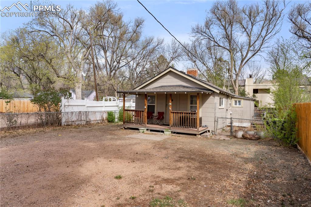 Image 2 of 15: Back of house featuring a fenced backyard, a chimney, and covered porch