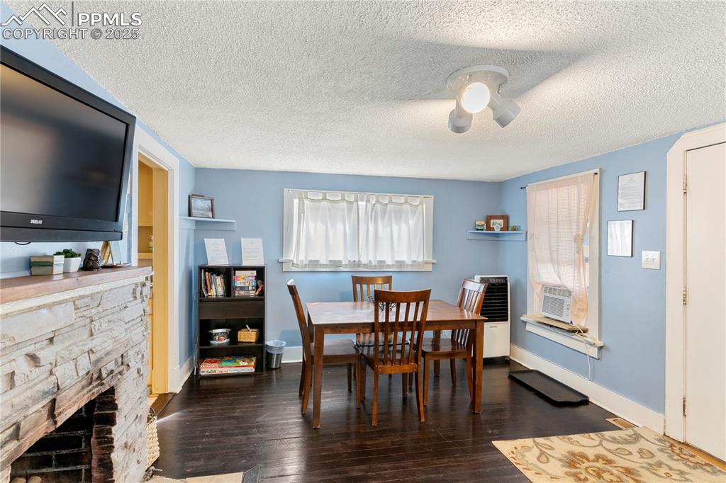 Image 3 of 15: Dining space with a textured ceiling, dark wood-type flooring, a fireplace,