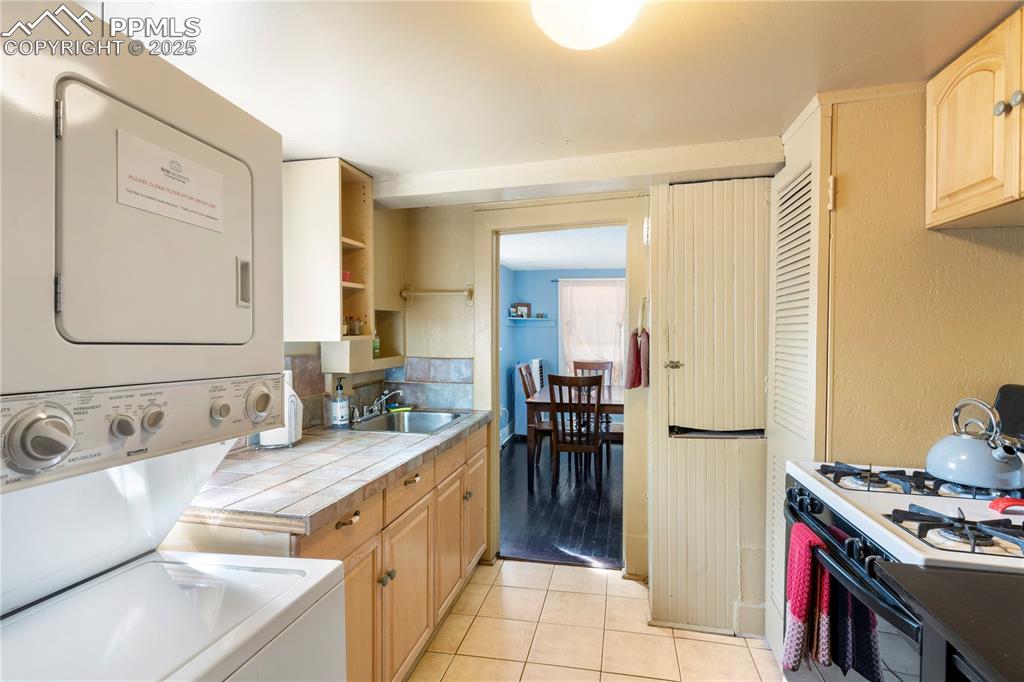 Image 5 of 15: Kitchen featuring tile countertops, white gas stove, light tile patterned f