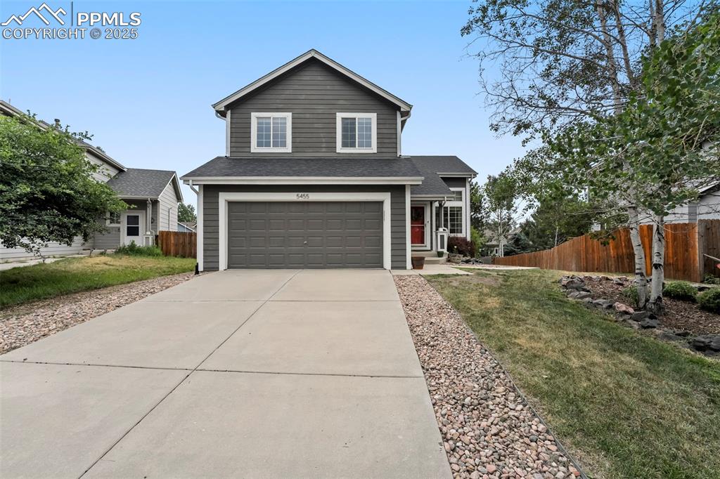 Caption: Traditional-style house with an attached garage, concrete driveway, and a shingled roof
