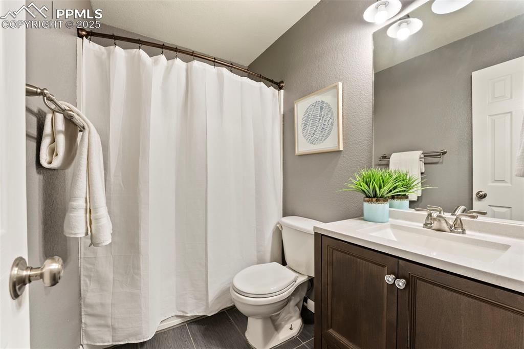 Image 19 of 31: Full bathroom featuring vanity, a textured wall, and curtained shower