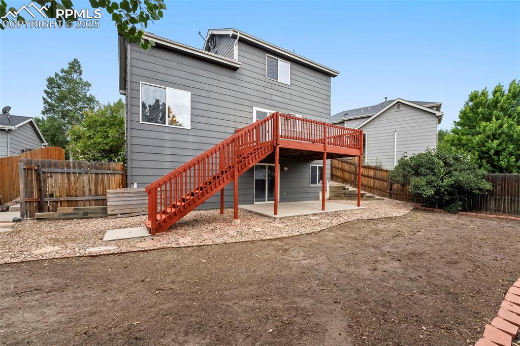 Image 23 of 31: Back of property with stairway, a wooden deck, a patio area, and a fenced b