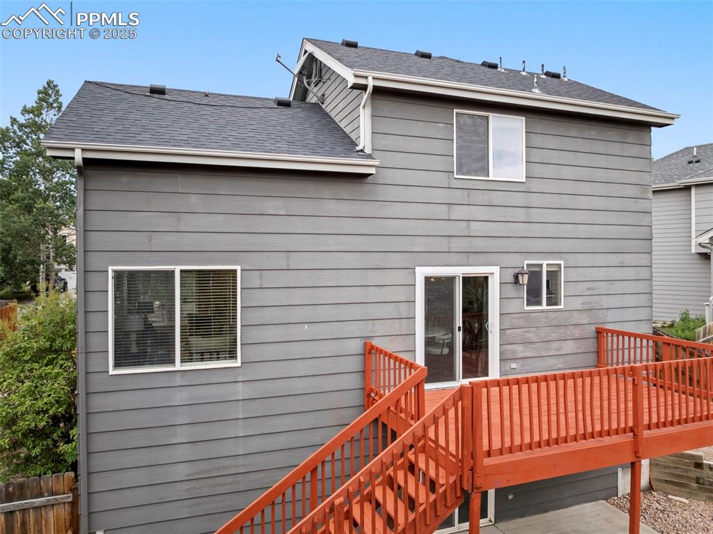 Image 30 of 31: Rear view of house featuring a wooden deck, roof with shingles, and stairwa