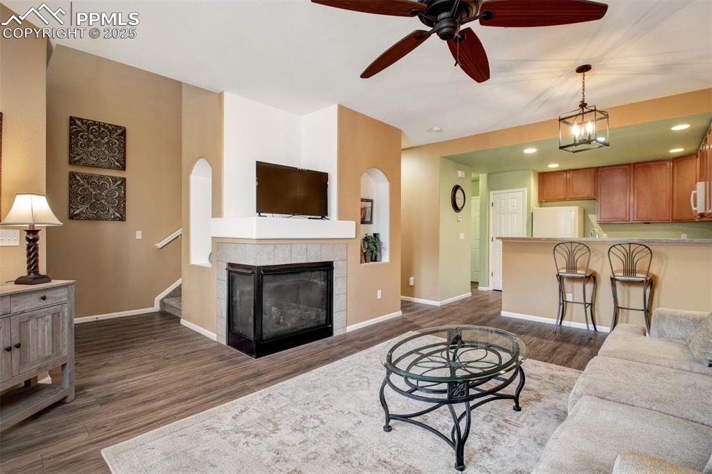 Image 2 of 24: Living room featuring a ceiling fan, a tiled fireplace, new flooring, reces