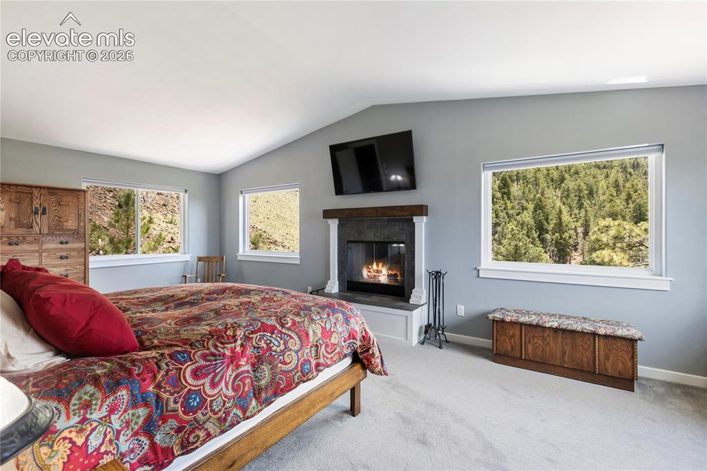 Image 17 of 31: Primary bedroom with a wood burning fireplace and plenty of views!