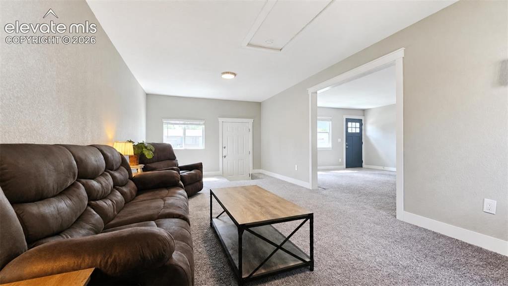Image 13 of 31: Carpeted living area with light-colored walls and white trim