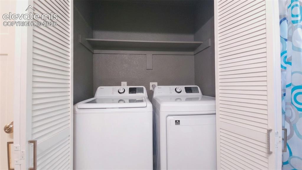 Image 20 of 31: Laundry closet with louvered bi-fold doors, built-in shelving, and white wa