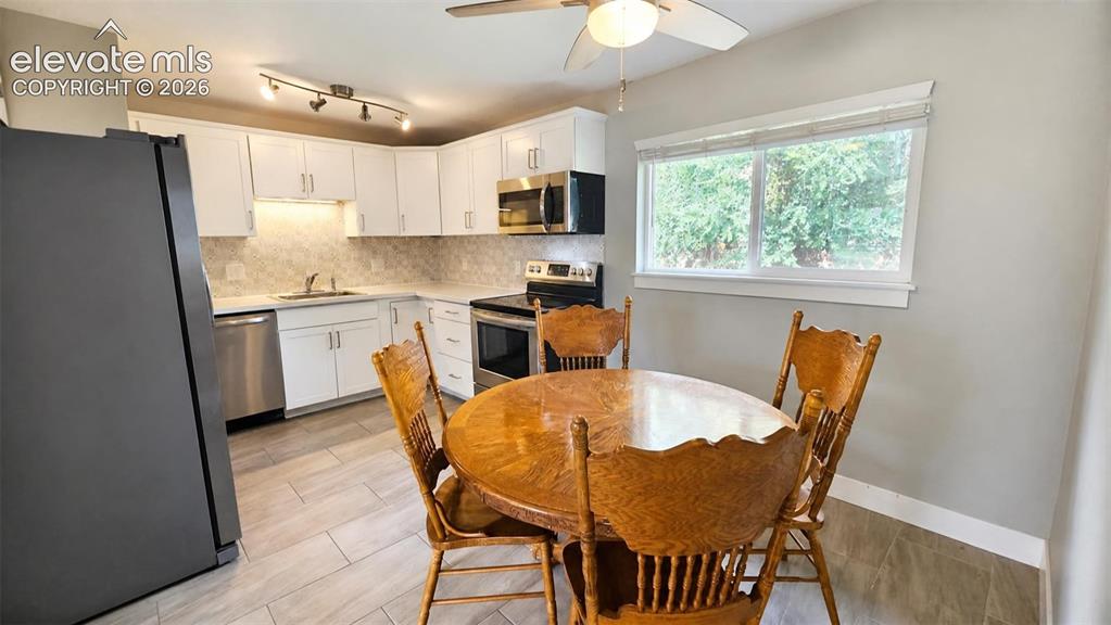 Image 6 of 31: Kitchen featuring white cabinetry, stainless steel appliances, a tile backs