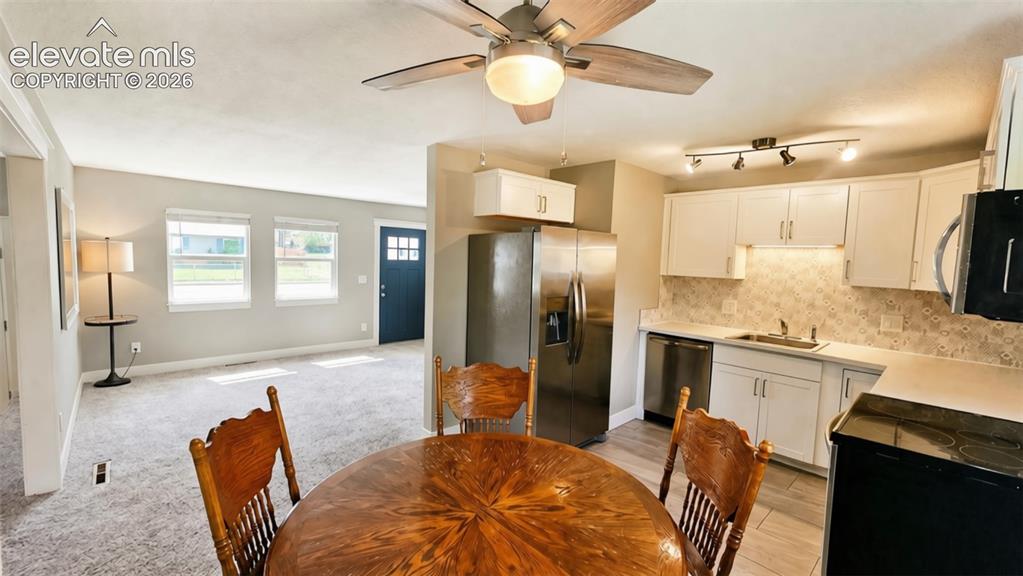 Image 9 of 31: Kitchen featuring white cabinetry, stainless steel appliances, a tile backs